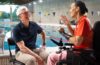 Apple CEO Tim Cook sat on a chair with a swimming pool in the background talking to Professional Paralympic Swimmer; Teresa Perales uses the Apple Watch for her insane training.