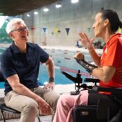 Apple CEO Tim Cook sat on a chair with a swimming pool in the background talking to Professional Paralympic Swimmer; Teresa Perales uses the Apple Watch for her insane training.